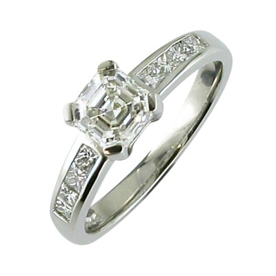Emerlad cut diamond single stone ring with princess cut channel set shoulders.