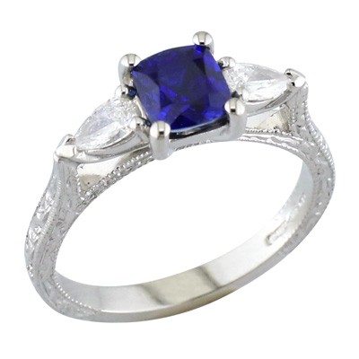 Cushion cut sapphire three stone ring with pear shaped diamonds and hand engraved shoulders